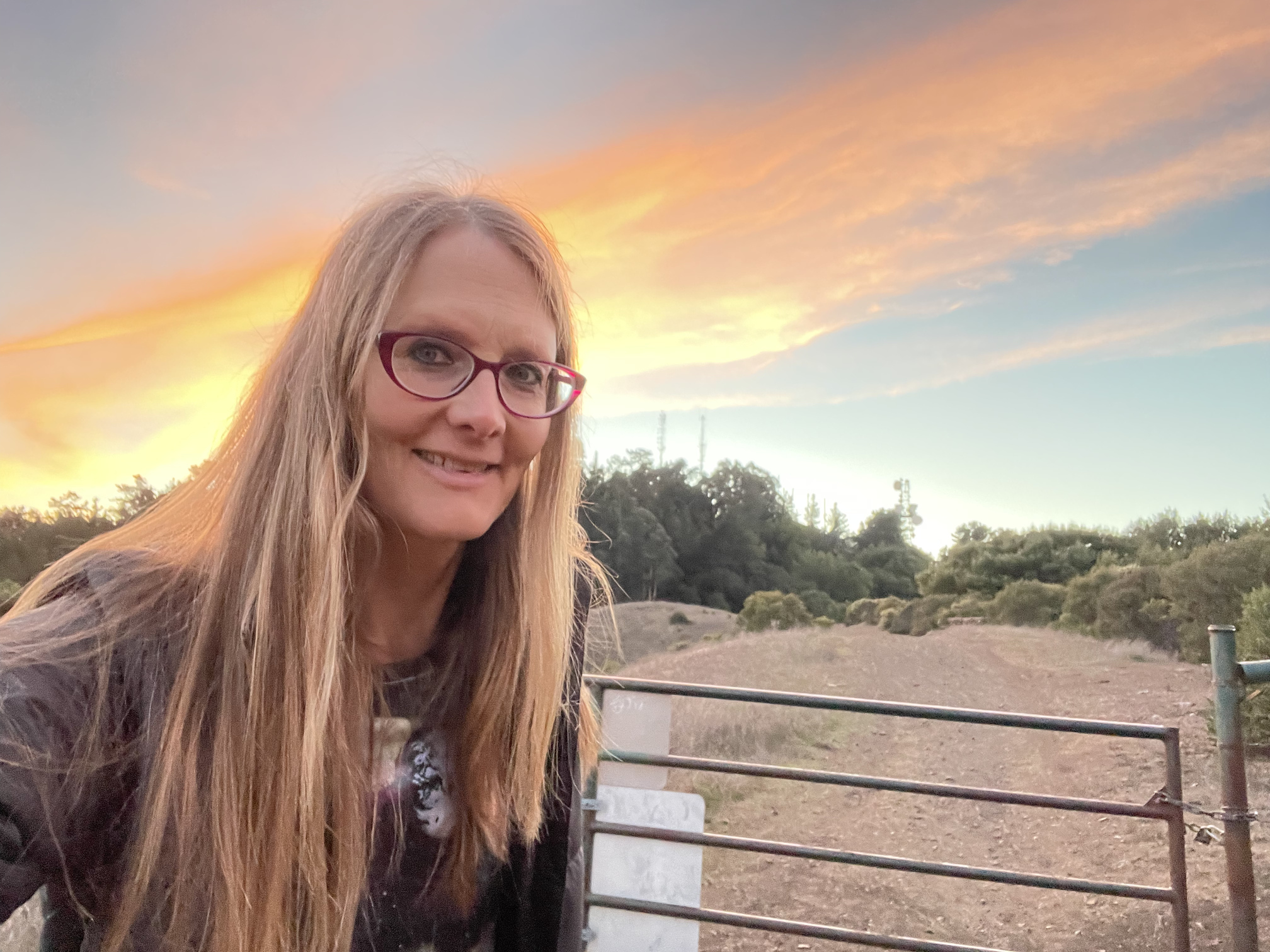tracey on fire road by gate with sunset