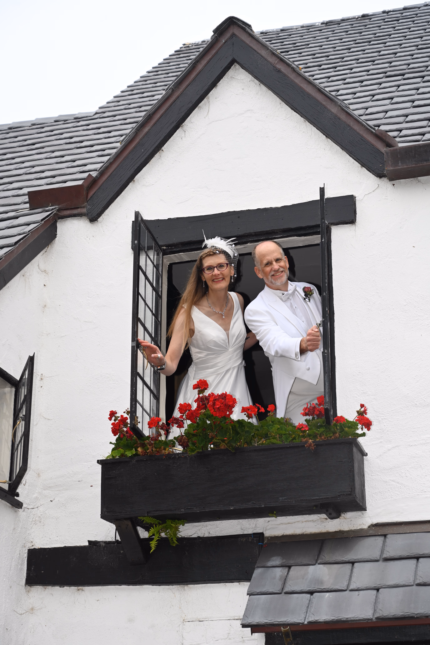 wedding couple leaning out window with flowers